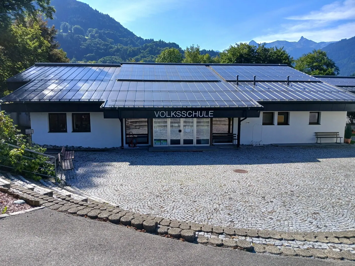 Die Volksschule St. Anton mit Pausenhof, dahinter die Berge des Montafons